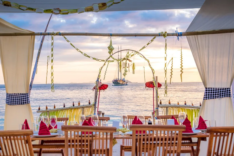 A festive dinner table laid on the deck of a Burgess charter yacht at sunset