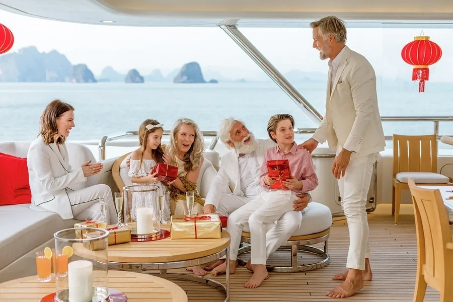 A family exchanging Christmas presents on the deck of a Burgess charter yacht